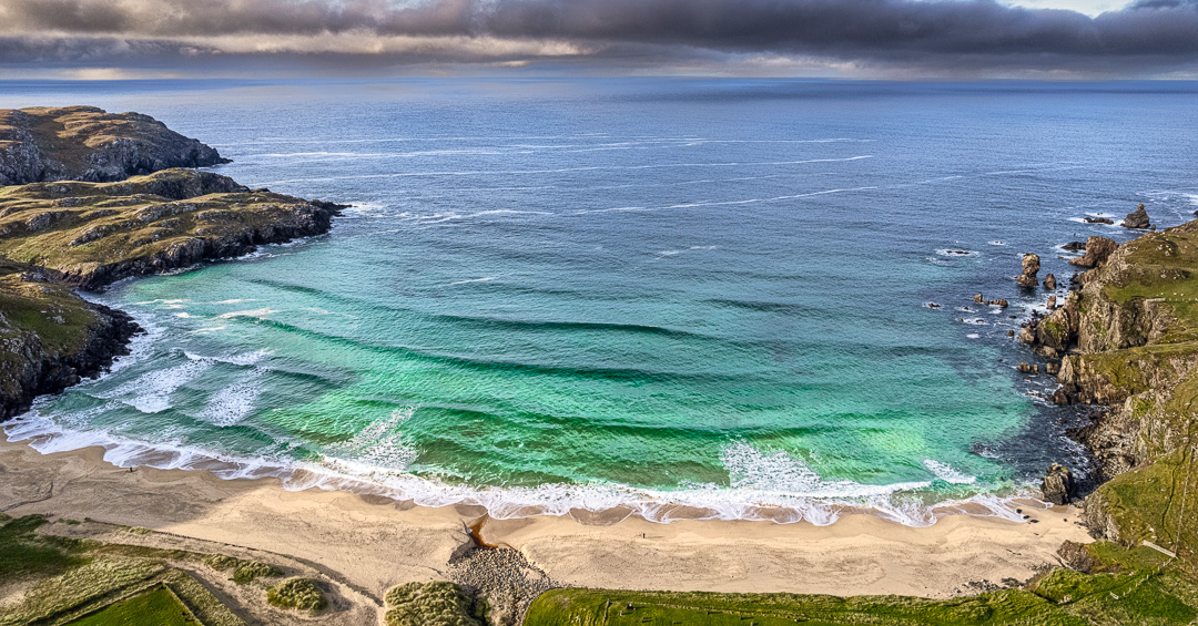 Aerial view of waves breaking on the golden sands of Dail Mòr beach. Hebridean beach photography on Isle of Lewis, Scotland.